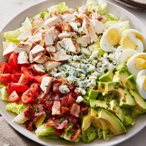 A colorful Cobb salad bowl with crisp lettuce, ripe tomatoes and hard-boiled eggs is served.
