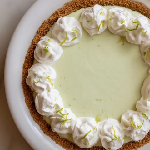 This Key Lime Pie shows a perfectly set, tart filling, garnished with fresh whipped cream.