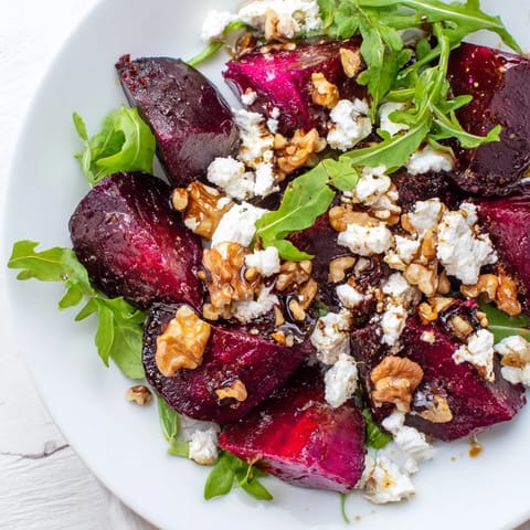 A close-up of Roasted Beet Goat Cheese Salad with glistening balsamic dressing, revealing the salad's tangy, sweet, and earthy textures and colors.