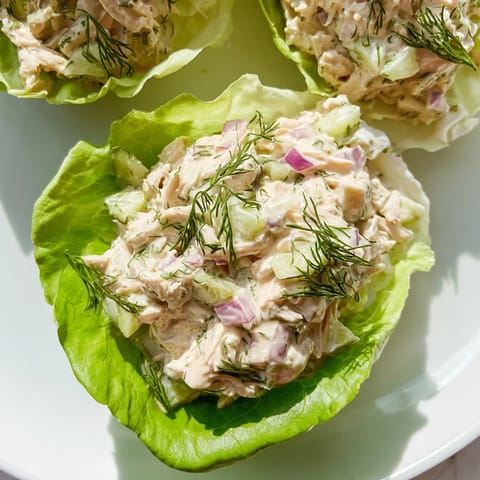 Freshly made Dill Pickle Chicken Salad Lettuce Cups served chilled with tangy dressing and vibrant red onion bits.  