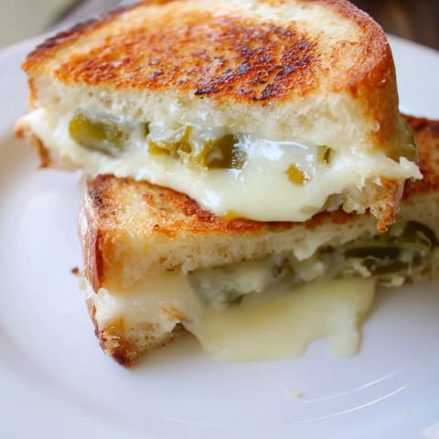 A close-up of a crispy Jalapeño Pepper Jack Grilled Cheese sandwich, oozing creamy cheese and tangy, spicy peppers.