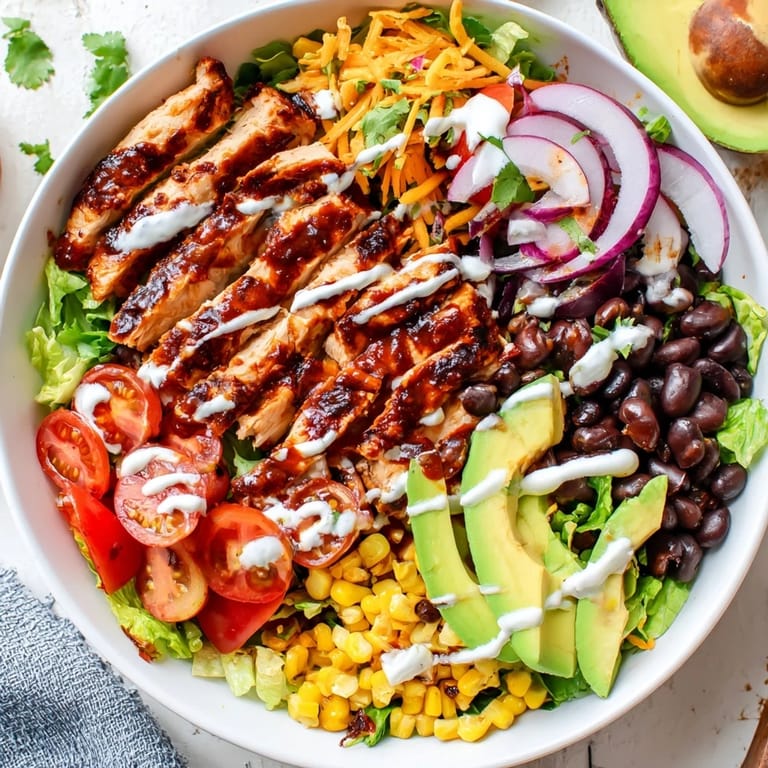 An overhead shot of BBQ Chicken Salad highlights colorful ingredients like cherry tomatoes, black beans, and corn, served in a rustic wooden bowl.