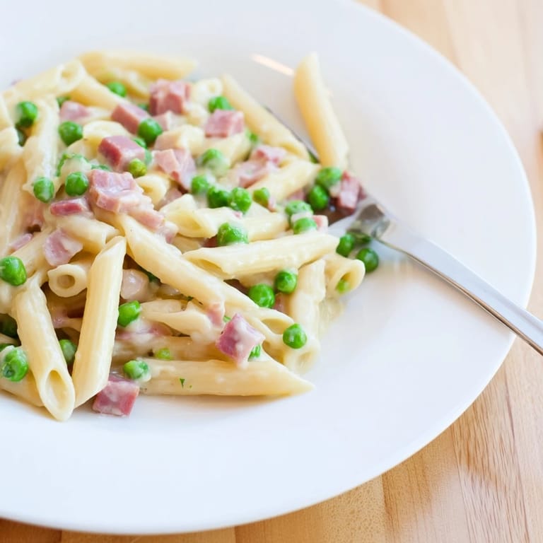 Colorful Spring Pea & Ham Pasta served steaming in a skillet, featuring bright green peas and golden ham pieces.