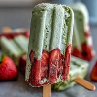 Creamy Strawberry Matcha Latte Popsicles with vibrant red and green layers, perfect for a refreshing spring dessert.  