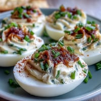 Classic deviled eggs with paprika and chives, creamy yolk filling piped into perfect halves and dusted with smoky spice.